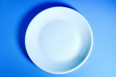 Empty white plate on blue background from top angle Stock Photos