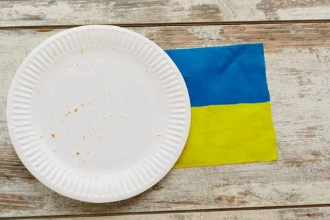 An empty white plate with bread crumbs stands on the Ukrainian flag, food pro Stock Photos