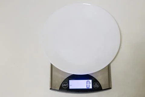 Empty white plate on digital kitchen scales close up. Modern electronic wei.. Stock Photos