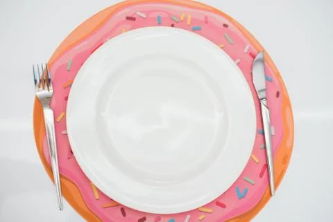 Empty white plate, fork and knife, on a donut rug, on a light background. Stock Photos