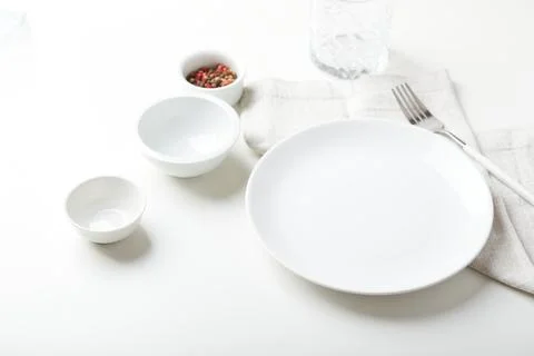 Empty white plate with a fork and small bowls on a light background Stock Photos