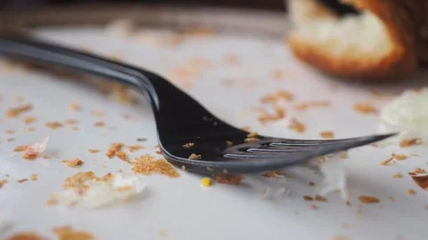 Empty white plate with fork crumbs and half eaten bun close up with dynamic.. Stockbeeldmateriaal 331836061