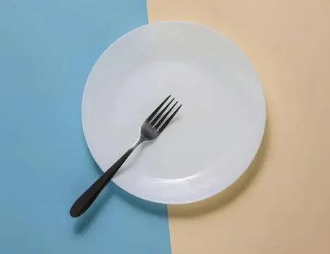 Empty white plate with fork on pastel colored background Foto stock