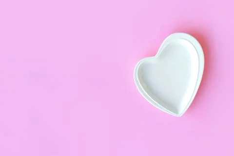 Empty white plate in the form of a heart on pink background for valentine's day Stock Photos