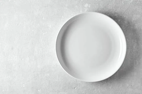 Empty white plate on a gray stone background. Template for displaying food on Stock Photos