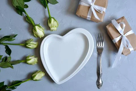 Empty white plate with hearts on Ultimate Gray background with white roses an Stock Photos