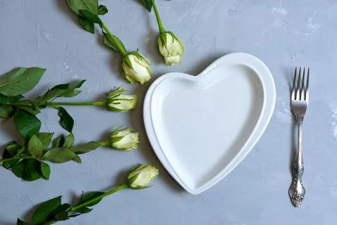 Empty white plate with hearts on Ultimate Gray background with white roses an Stock Photos