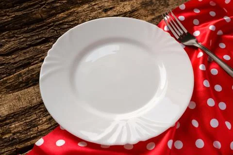 Empty white plate on a red napkin on the table Stock Photos