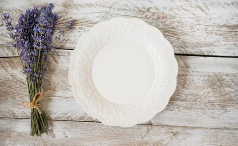 An empty white plate with a relief pattern stands on a vintage  background. Stock Photos