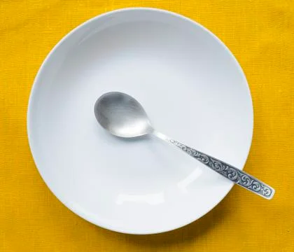 Empty white plate with silver spoon Stock Photos