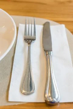 Empty white plate with spoon and knife on wooden background Foto stock