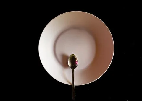 Empty white plate with spoon on black background minimal concept Stock Photos
