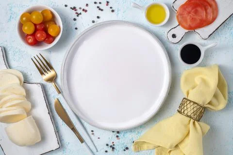 Empty white plate surrounded by cutlery and fresh vegetables Stock Photos