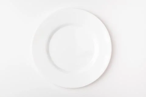 An empty white plate on a white background. Blank plate. Top view. Stock Photos