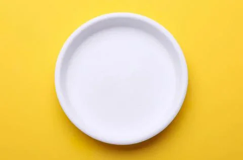Empty white plate on yellow background Foto stock