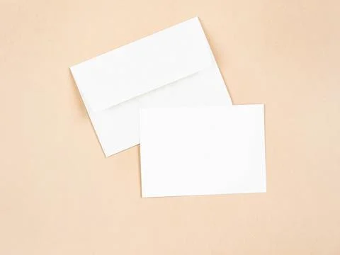 Empty white postcard and envelope on beige background. Stock Photos