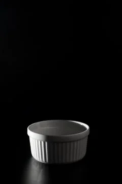 Empty white Ramekin on black background with copy space. Stock Photos