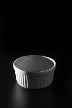 Empty white Ramekin on black background with copy space. 스톡 사진