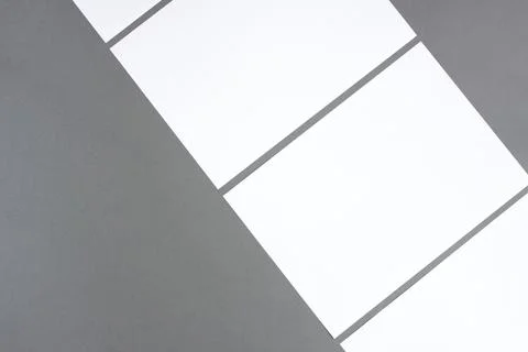 Empty white rectangle poster mockups lying diagonally on a dark gray background Stock Photos