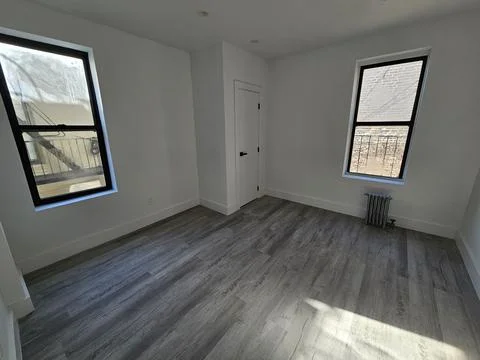 Empty white room with grey laminate floor, black windows and radiator Stock Photos