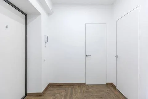 Empty white room with two closed doors and wooden floor Stock Photos