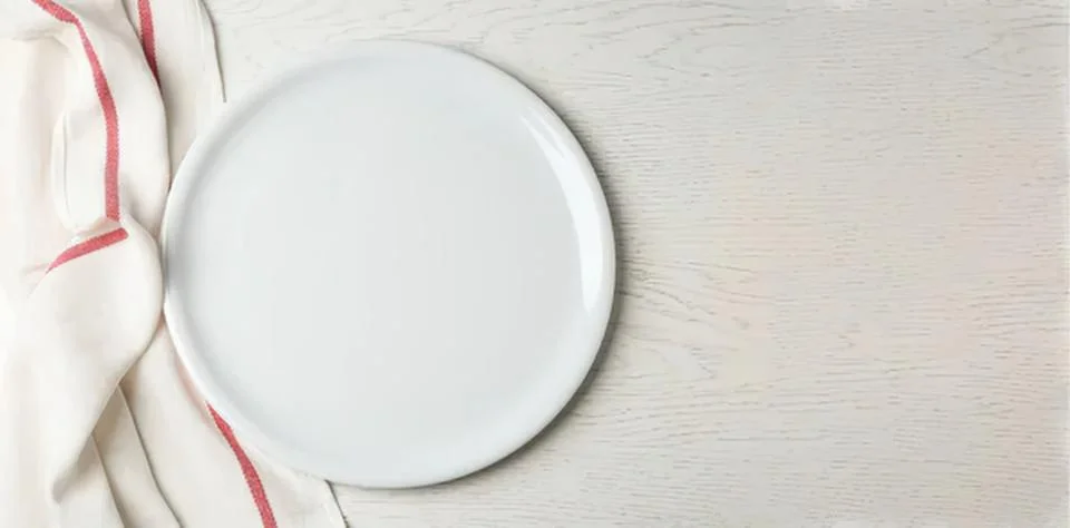Empty white round plate on light wooden table with cloth Stock Photos
