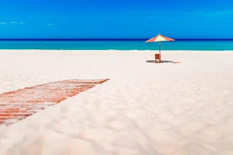 Empty white sand beach and parasol, blue sky Stock Photos