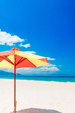 Empty white sand beach and parasol, blue sky Stock Photos