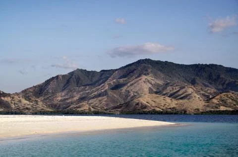 Empty white sand beach with blue ocean overlooking mountain landscape, Flores. Stock Photos