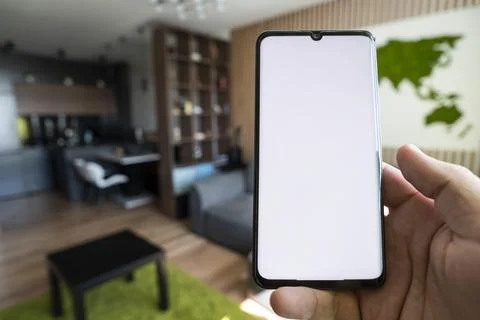 Empty white screen on smartphone on background of a beautiful cozy modern d.. Stock Photos