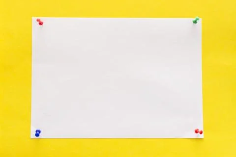 Empty white sheet of paper pinned with push pins on a yellow background Stock Photos