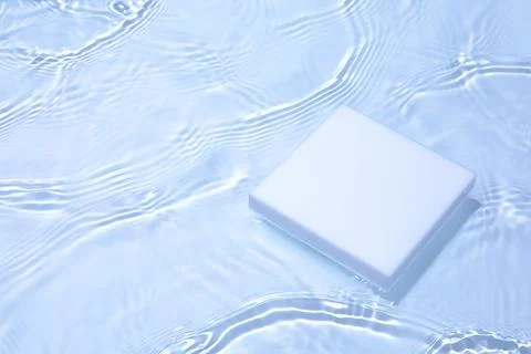 Empty white square podium on transparent clear blue water background Stock Photos