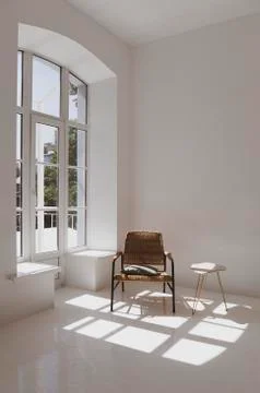 Empty white sunny room with wicker chair and table. Minimalist design Stock Photos