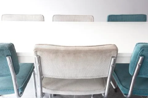 Empty white wooden dining table with modern chairs in white room, closeup Stock Photos