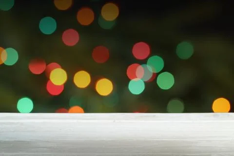Empty white wooden table in front of blurred christmas lights background Foto stock