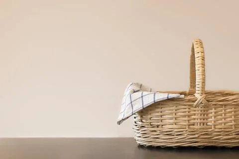 Empty wicker basket on dark table top with neutral beige background. Template 库存照片
