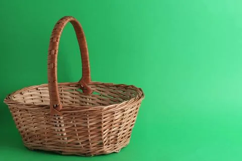 Empty wicker basket on green background, space for text. Easter item Stock Photos