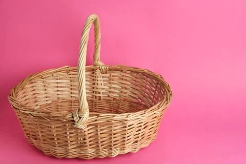 Empty wicker basket on pink background, space for text. Easter item Stock Photos