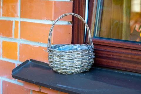 An empty wicker basket is placed on the windowsill outside Fotos Stock
