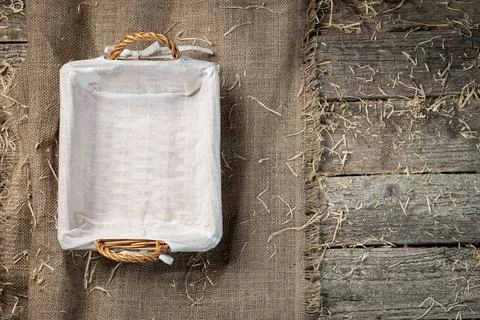 Empty wicker bread basket with white napkin on burlap cloth covered with stra Stock Photos