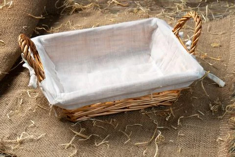 Empty wicker bread basket with white napkin on burlap cloth covered with stra Stockfoto's