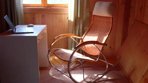 An empty wicker rocking chair made of wood sways in the sun in a country hous Stock Footage 152568945