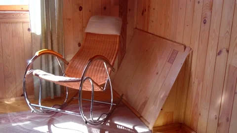 An empty wicker rocking chair made of wood sways in the sun in a country hous Stock Footage 152569034