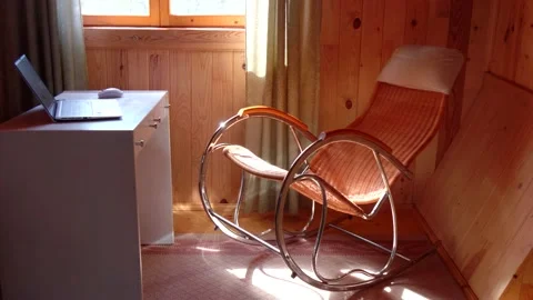 An empty wicker rocking chair made of wood sways in the sun in a country hous Stock Footage 152570437