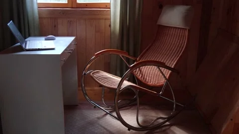 An empty wicker rocking chair made of wood sways in the sun in a country hous Stock Footage 152570441