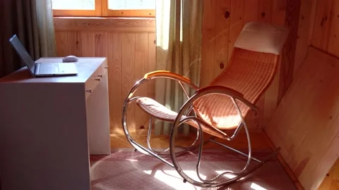 An empty wicker rocking chair made of wood sways in the sun in a country hous Stock Footage 152570494