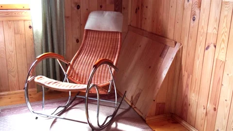 An empty wicker rocking chair made of wood sways in the sun in a country hous Stock Footage 152576000