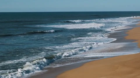Empty wide beach landscape shot of big waves and small surfers surfing Stock Footage 273795654