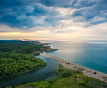 An empty wild beach, surrounded by rocks and green thick forests Stock Photos