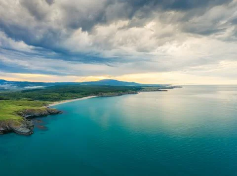 An empty wild beach, surrounded by rocks and green thick forests Stock Photos